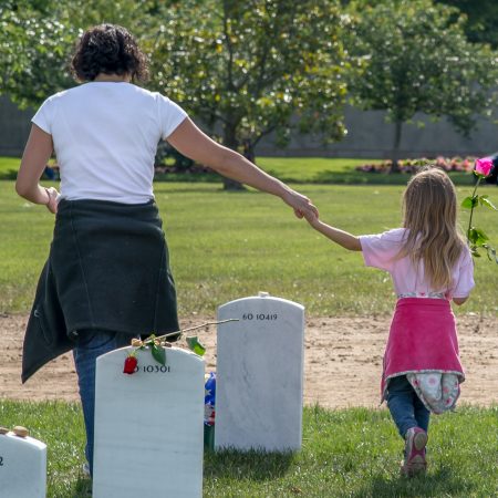 Mother and child holding rose at Memorial Day at Arlington National Cemetery in Virginia.