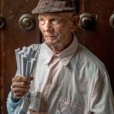 Elderly Cuban man selling rolls of peanuts.