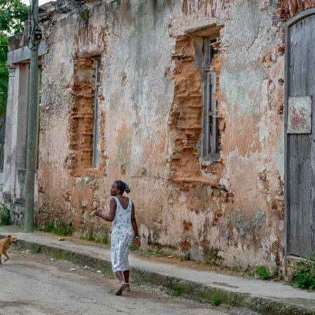 Girl running down street with dog in Cojimar, Cuba.
