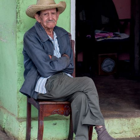 Elderly man with cowboy hat seated in doorway in Vinales, Cuba.