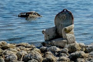 Abandoned upholstered chair beach and at water's edge in Salton Sea, California.