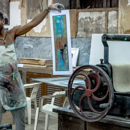 Artist revealing print in Havana art studio.