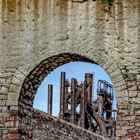 Rusty Abandoned Bethlehem Steel Blast Furnace framed by old brick factory ruins.